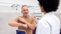 Mature Latin American patient talking to an orthopedist about pain in his shoulder.