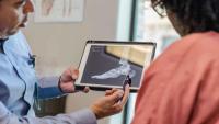 Clinician showing an ankle X-ray on a tablet to a patient.