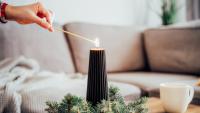 woman lighting a holiday candle on a coffee table