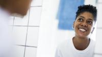 black woman smiling in bathroom mirror