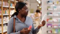 black woman reading label on a personal care product