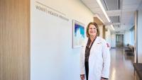 Doctor standing beside the Women’s Health Program sign.
