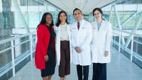 Four cardio-oncology clinicians standing together in a hospital corridor.