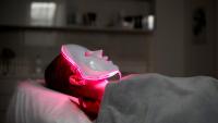 woman laying down wearing a red light therapy mask