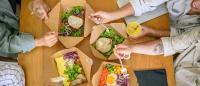 Overhead view of people eating salads together at a table.