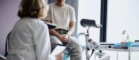 a patient sits on an exam table and listens to her gynecologist