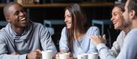 4 friends laughing and sipping coffee