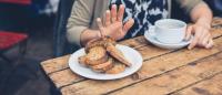 Person pushing away plate of bread on a table