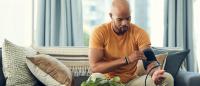 man sitting on sofa and measuring his blood pressure