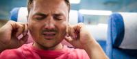 man having ear pain on airplane