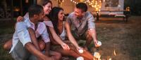 group of people roasting marshmellows by campfire