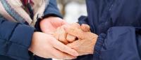 two older people holding hands in cold weather outside