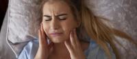woman experiencing jaw pain in bed
