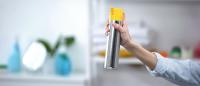 woman spraying air freshener in a house