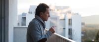 older man smoking on a balcony