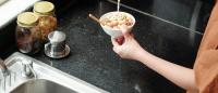 woman pouring raw milk on cereal