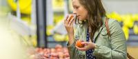 woman smelling fruit in a grocery store