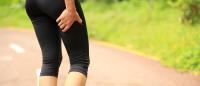 woman holding hamstring area in running clothes