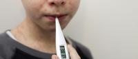 photo of a boy with a thermometer in mouth and marks on skin