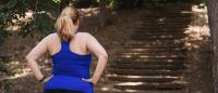 Woman holding hands on hips when observing stairs in a park that she was about to run on.
