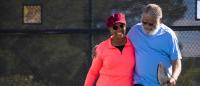 A senior African American couple playing pickle ball at the park.