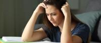 woman experiencing anguish while looking at notebooks and studying