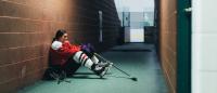 young woman hockey player sitting in an alley against the wall