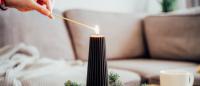 woman lighting a holiday candle on a coffee table