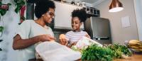 Mother and daughter talking and unpacking fruits and vegetables in the kitchen at apartment