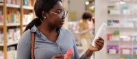 black woman reading label on a personal care product