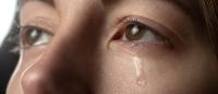 A tear rolls down a person's cheek from their eye, conveying sadness, grief, or pain.