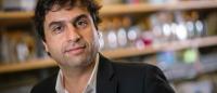 A photo of Hashim Al-Hasmii wearing a suit in his lab