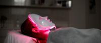 woman laying down wearing a red light therapy mask